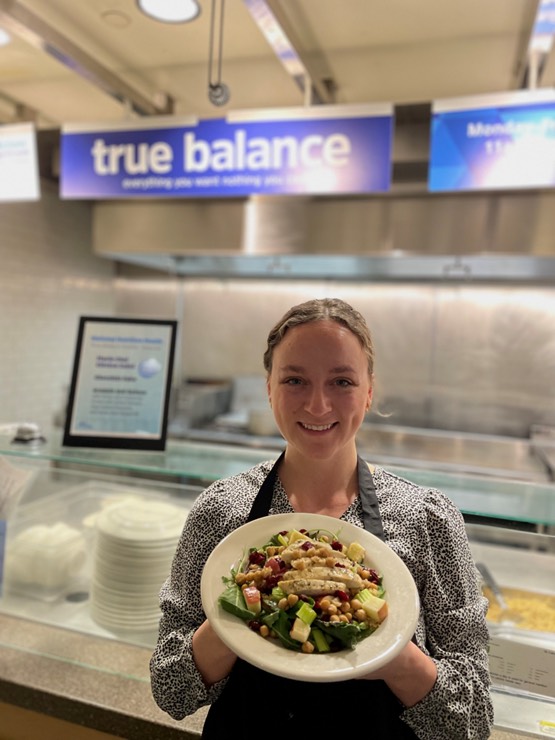 Registered Dietitian Alyssa, holding a plate of food in front of True Balance.